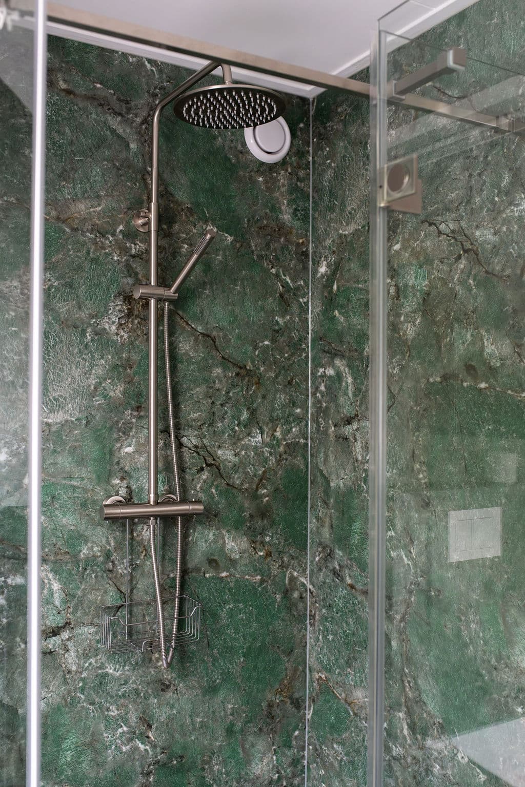 Luxuriöser Regenduschkopf vor grüner Marmorwand