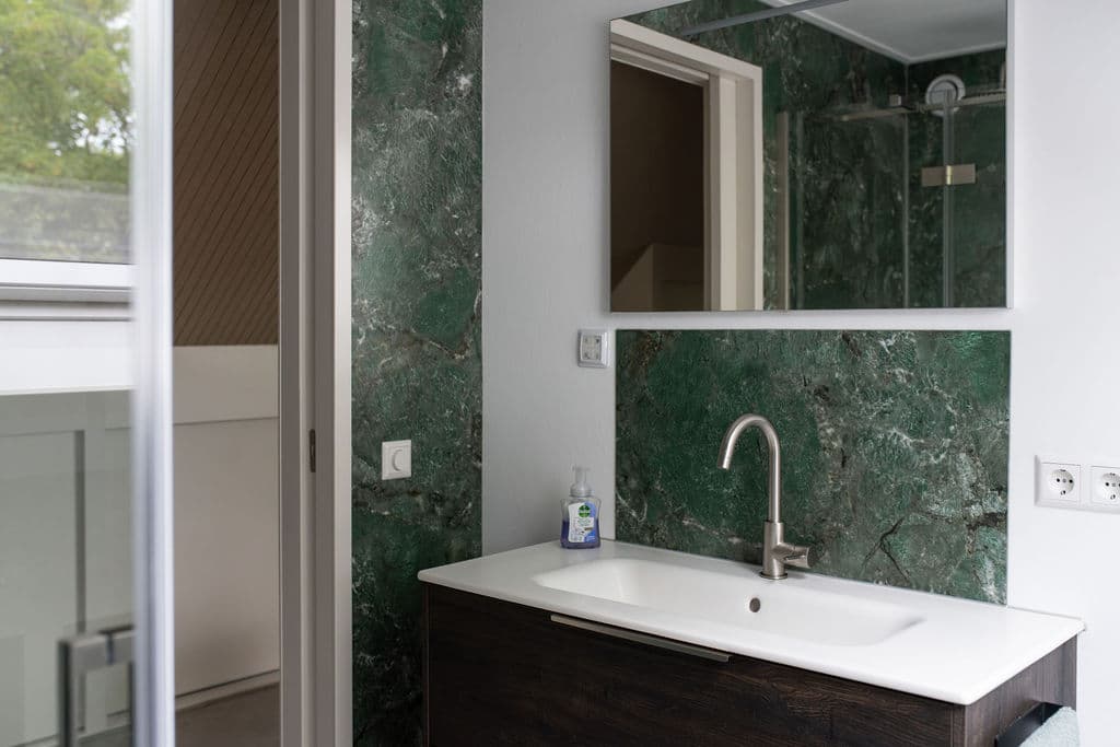 Badezimmer mit geöffneter Tür zum Treppenabsatz — Blick zum Waschtisch