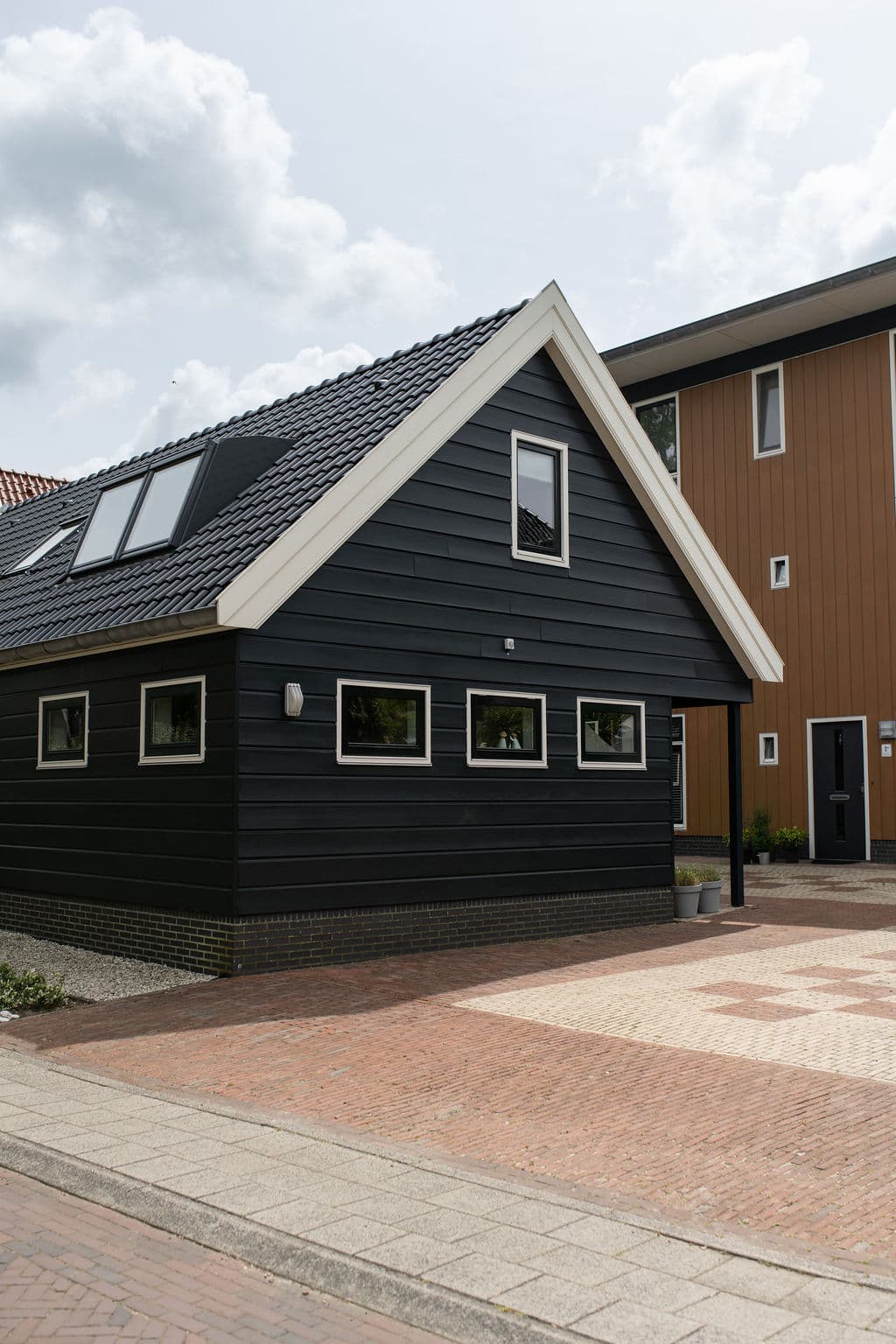 Weite Seitenansicht der schwarzen Holzfassade mit Nachbarhaus Schagen