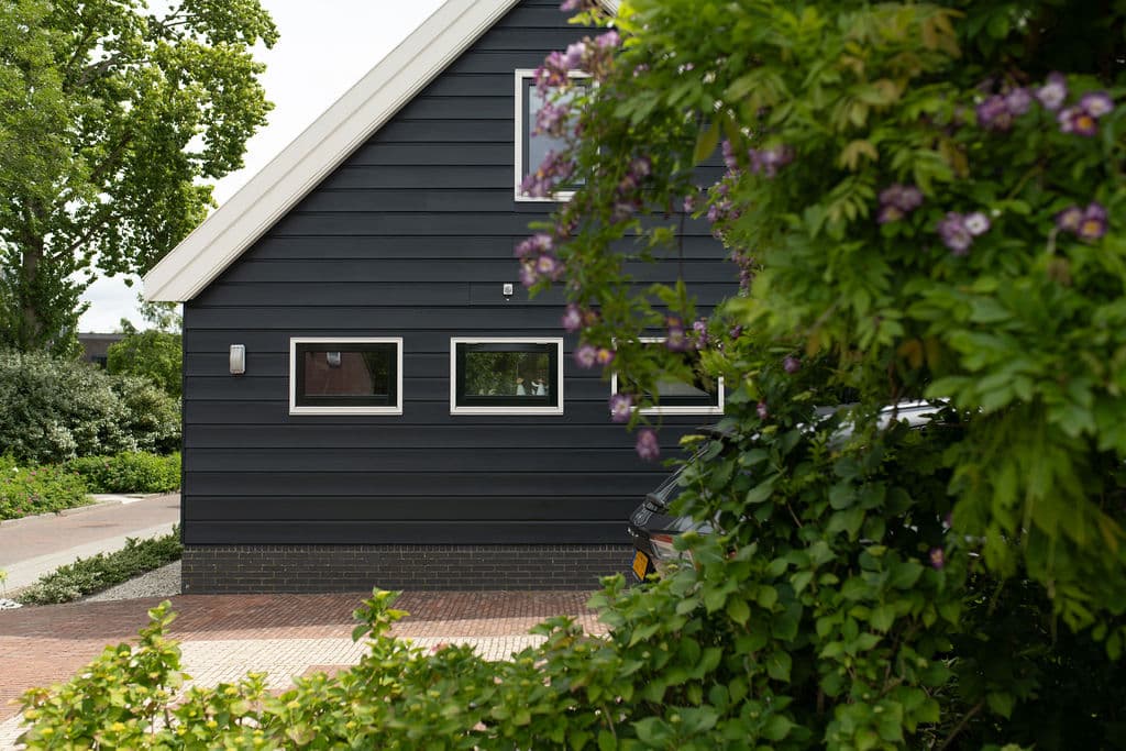 Seitenansicht des Appartements umgeben von Grün und lila Blumen