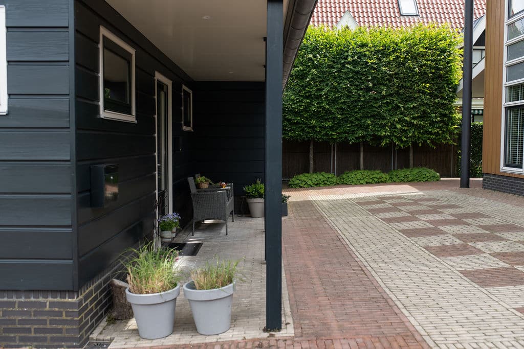 Überdachte Terrasse mit Korbstühlen und Pflanzkübeln Schagen