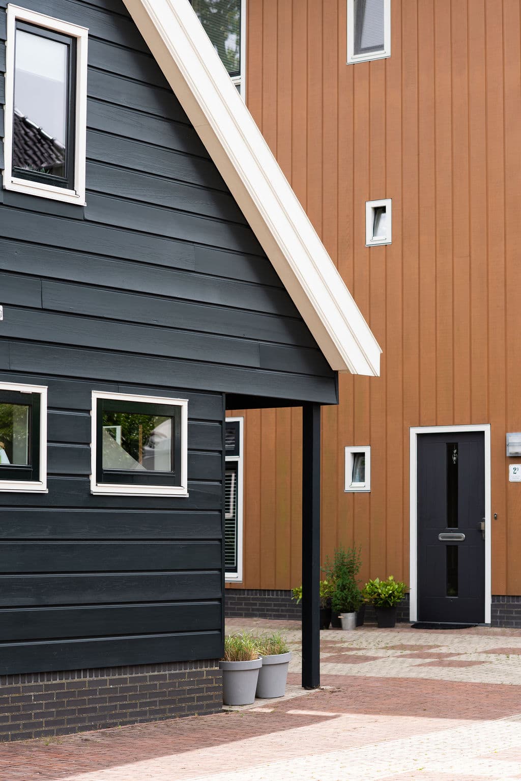 Schwarze Fassade des Ferienhauses Hannes neben warmem Holznachbarn