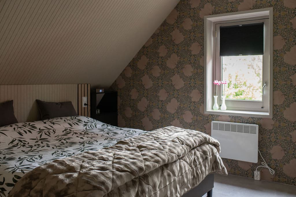 Schlafzimmer mit Blumenmuster-Bettwäsche und William-Morris-Tapete