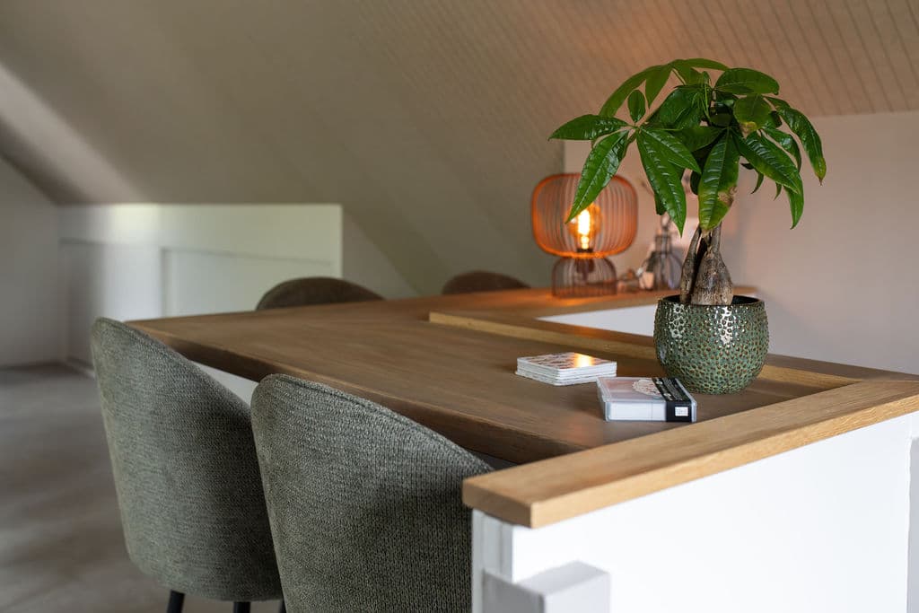 Stimmungsvolle Dachgeschoss-Ecke mit orangener Lampe und grünen Stühlen